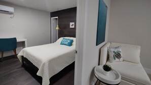 A modern bedroom with a bed, a desk, a chair, a small table with a plant, and a couch. - 10 Min Brickell & Miami Beach /Parking/Wi-Fi/Grill (Miami)