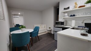 A modern kitchen with white cabinetry, a microwave, a sink, and a dining area with blue chairs and a white table. - 10 Min Brickell & Miami Beach /Parking/Wi-Fi/Grill (Miami)