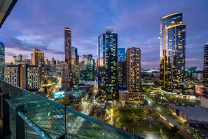A cityscape at dusk with illuminated skyscrapers and a busy street below. - Mega Style Apartments Mainpoint (Southbank)