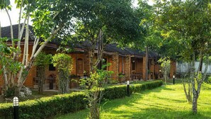 A traditional brick building with a tiled roof, surrounded by lush greenery and a well-maintained lawn. - Bungalow with king double bed (Krabi)