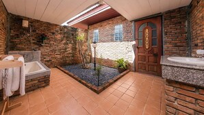 A bathroom with a bathtub, a sink, and a shower. There is a small garden area with plants and a decorative door.