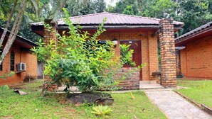 A small brick house with a red roof, a brick chimney, and a door with a window above it.