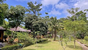A lush garden with a variety of trees and a small building with a red roof.