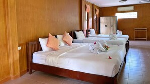 A hotel room with three beds, wooden walls, and a tiled floor.