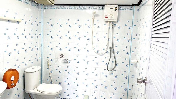 A bathroom with a toilet, a shower, and a hand dryer.