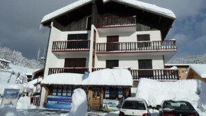 Un hotel a più piani con balconi, immerso in un paesaggio innevato.