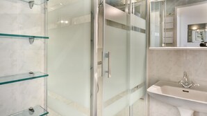 Un bagno moderno con doccia vetrata, lavandino bianco e specchio sopra il lavandino.