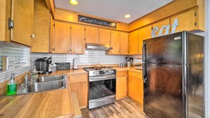 A kitchen with wooden cabinets, stainless steel appliances, and a sign that says "eat." - Deep Gap Cottage w/ Fire Pits - Hike & Ski! (Deep Gap)