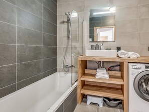 A modern bathroom with a bathtub, a shower, a sink, and a built-in washing machine. - Luxury apartment, 4 rooms, 8 people, large terrace, Champagny-en-Vanoise (Champagny-en-Vanoise)