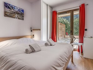 A hotel room with a large bed, a desk, and a balcony with red curtains. - Luxury apartment, 4 rooms, 8 people, large terrace, Champagny-en-Vanoise (Champagny-en-Vanoise)