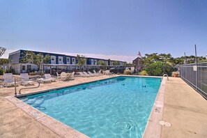 Una piscina con lettini e un edificio sullo sfondo.