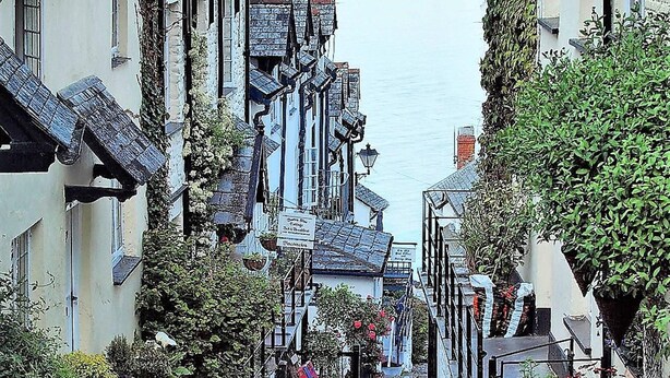 Une ruelle étroite pavée, bordée d’immeubles aux toits très pentus, dont certains arborent des enseignes bien visibles.