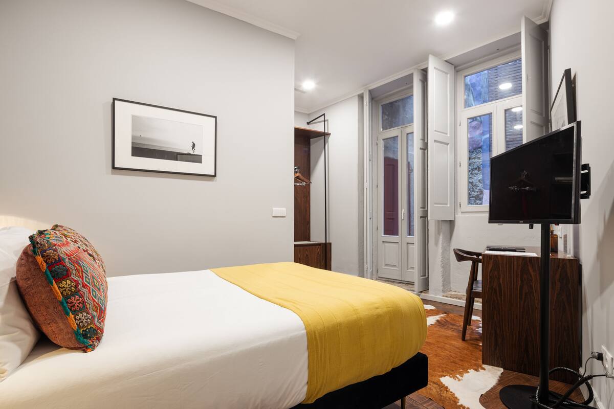 Une chambre à coucher avec un lit, une télévision, un bureau et une fenêtre.