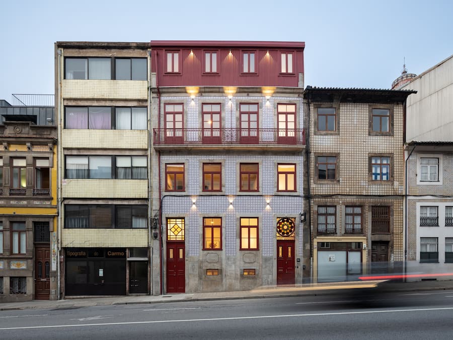 Una hilera de edificios de varios pisos con estilos arquitectónicos diferentes, incluyendo un edificio con fachada roja y ventanas con diseños.