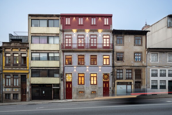 A row of multi-story buildings with distinct architectural styles, including a building with a red facade and patterned windows. - Utopian - Design Suites Porto (Porto)