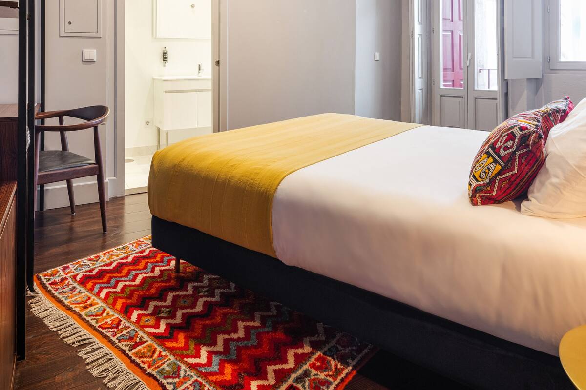 Une chambre à coucher avec un lit, un téléviseur fixé au mur, une porte donnant sur une salle de bain et une fenêtre avec vue.