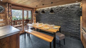 A wooden dining area with a stone wall, wooden ceiling, and a view of the outdoors. - Modern Duplex in Méribel Village, ski-in/ski-out access and pool (Méribel)