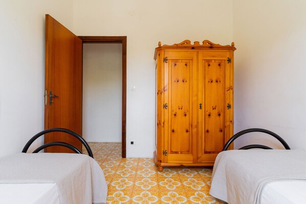 A room with two beds, a wooden wardrobe, and a patterned floor.
