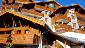 Un chalet en bois à plusieurs étages, doté de balcons et d’une façade en pierre.