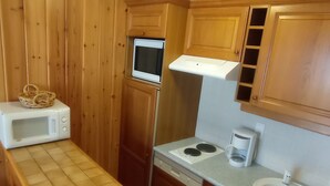 Une cuisine compacte dotée d’armoires en bois, d’un four à micro-ondes, d’une cuisinière, d’un évier et d’une machine à café.
