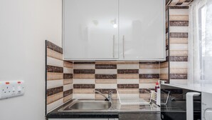 Une cuisine avec des meubles blancs, un plan de travail noir et un pare-feu en carreaux.