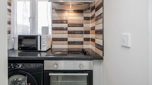 Une cuisine compacte équipée d’un lave-linge, d’un four à micro-ondes, d’une cuisinière et d’un four.
