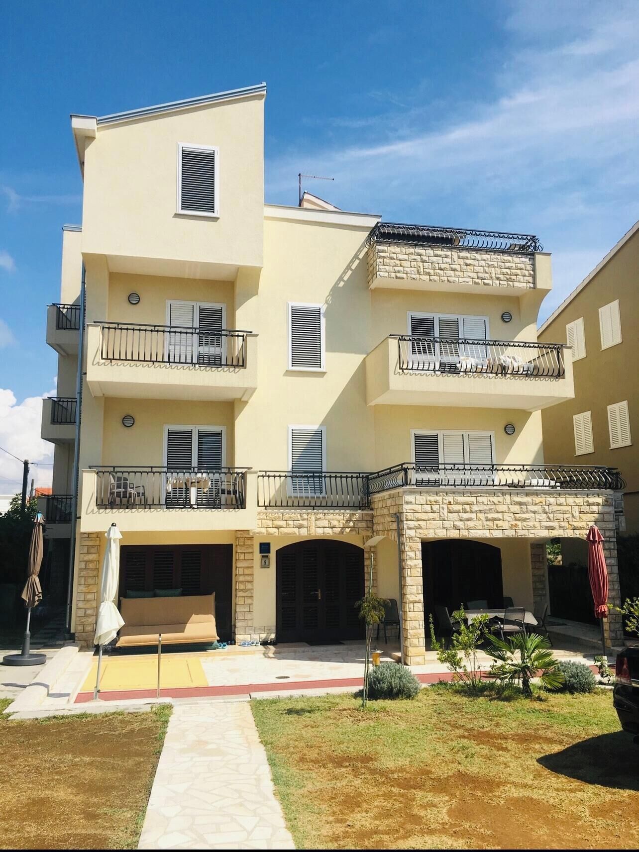 Um edifício residencial com vários andares, varandas, fachada de pedra e área coberta para estar ao ar livre.