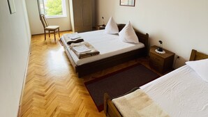 Une chambre avec un plafond en bois, un lit recouvert de draps blancs, une table de chevet, une chaise et une armoire.