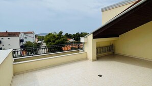 Un balcon spacieux doté d’un sol carrelé et d’une rambarde en métal.