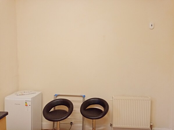 Een kamer met een witte radiator, een wit apparaat en twee zwarte stoelen met een metalen frame.
