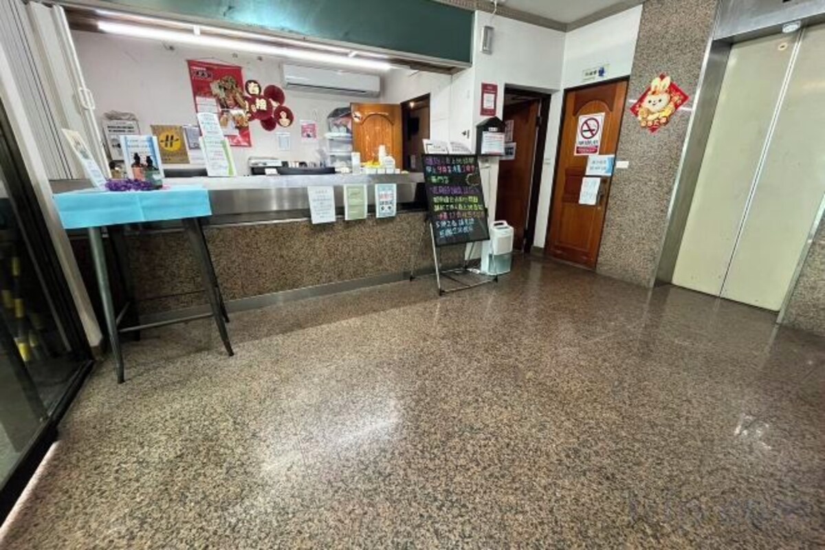Un espace d’accueil avec un comptoir, un tableau affichant le menu au mur et un panneau indiquant qu’il est interdit de fumer.