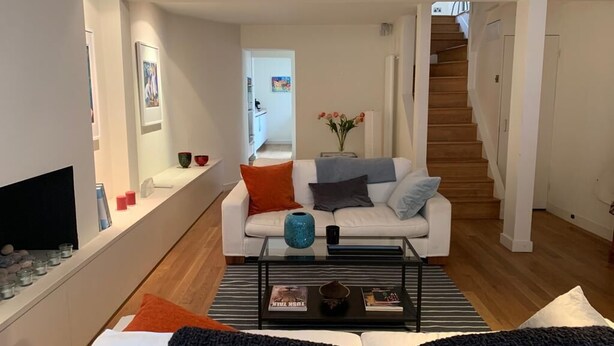A modern living room with a white sofa, a coffee table, and a staircase leading to another level. - Fully furnished house in Kensington, bordering on Notting Hill (London)