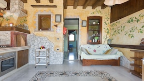 A cozy living room with a stone fireplace, wooden beams, a sofa, and a tiled floor. - 3110 Attico Nereide by Barbarhouse (Gallipoli)