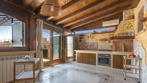 A rustic kitchen with wooden beams, a stone wall, and a tiled floor. - 3110 Attico Nereide by Barbarhouse (Gallipoli)
