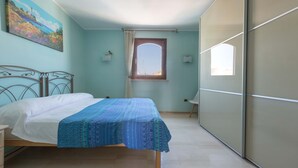 A bedroom with a bed, a window, a painting on the wall, and a wardrobe. - 3110 Attico Nereide by Barbarhouse (Gallipoli)