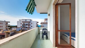 Ein Balkon mit Tisch und Stühlen, einer Schiebetür und Blick auf benachbarte Gebäude.