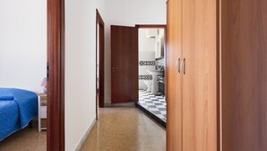 Ein Flur mit einem Bett, einem Holzschrank und einem Badezimmer mit Schachbrettboden.