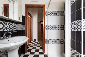Un baño con suelo a cuadros, lavamanos y azulejos estampados.