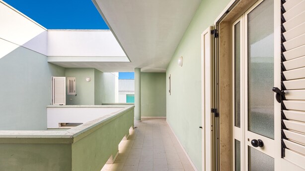 A corridor with a skylight, a door with a frosted glass panel, and a light green wall. - 2716 Baia Verde Apartments - Appartamento Timone (Gallipoli)