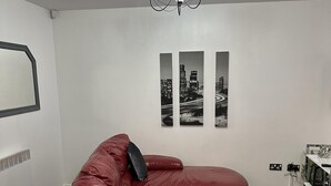 A modern living room with a red leather sectional sofa, a black and white cityscape wall art, and a white radiator. - Remarkable 2-bed Apartment in Wolverhampton (Wolverhampton)