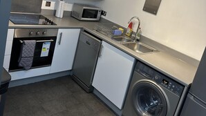 A compact kitchen with a built-in oven, microwave, dishwasher, and washing machine. - Remarkable 2-bed Apartment in Wolverhampton (Wolverhampton)