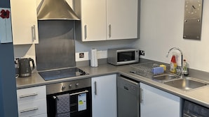 A compact kitchen with a stove, microwave, sink, and dishwasher. - Remarkable 2-bed Apartment in Wolverhampton (Wolverhampton)