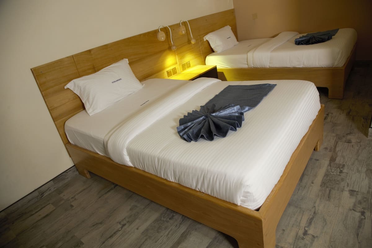 Ein Hotelzimmer mit zwei Einzelbetten, Holz-Kopfteilen und Holzboden.