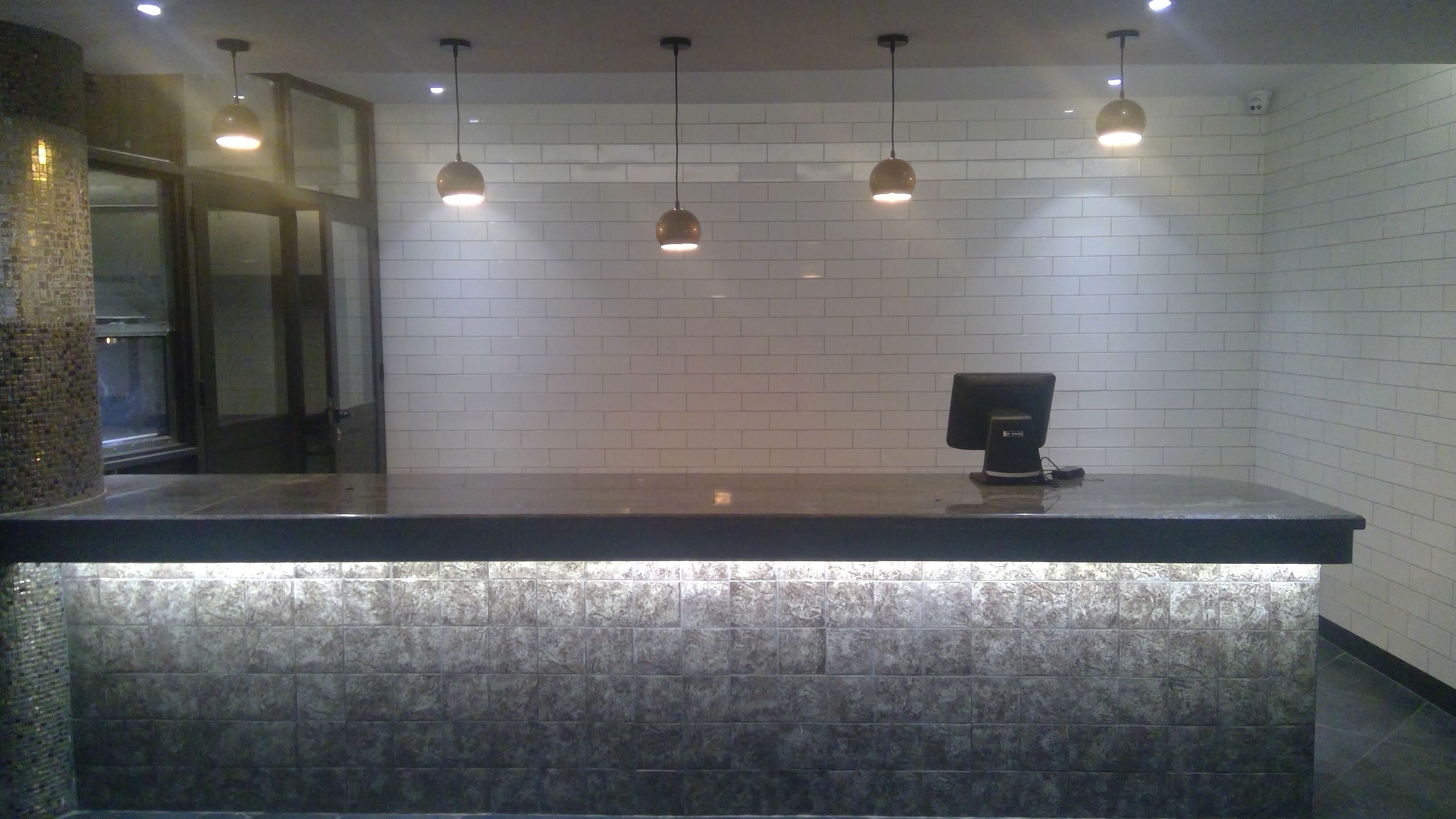 A reception desk with a modern design, featuring a marble-like countertop and a digital screen.
