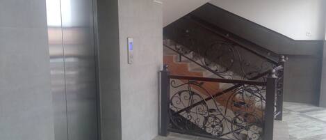 A staircase with ornate metal railings and a modern elevator adjacent to it.