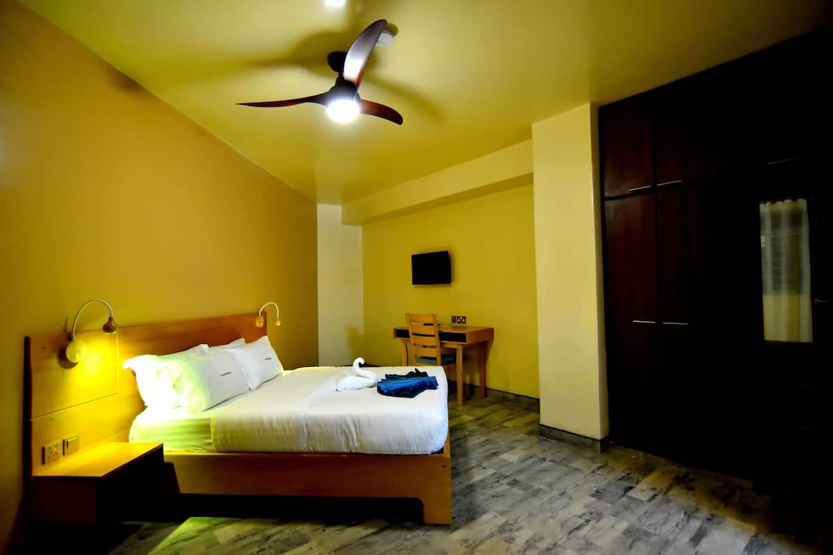 Ein Hotelzimmer mit Bett, Nachttisch, Schreibtisch, Stuhl und Kleiderschrank.