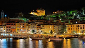 A waterfront cityscape at night with illuminated buildings and a prominent castle-like structure.