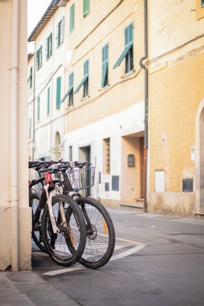 A bicycle parked against a building with a yellow facade and green shutters.
