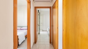 Un couloir avec des portes en bois et un appareil de climatisation blanc placé en hauteur.