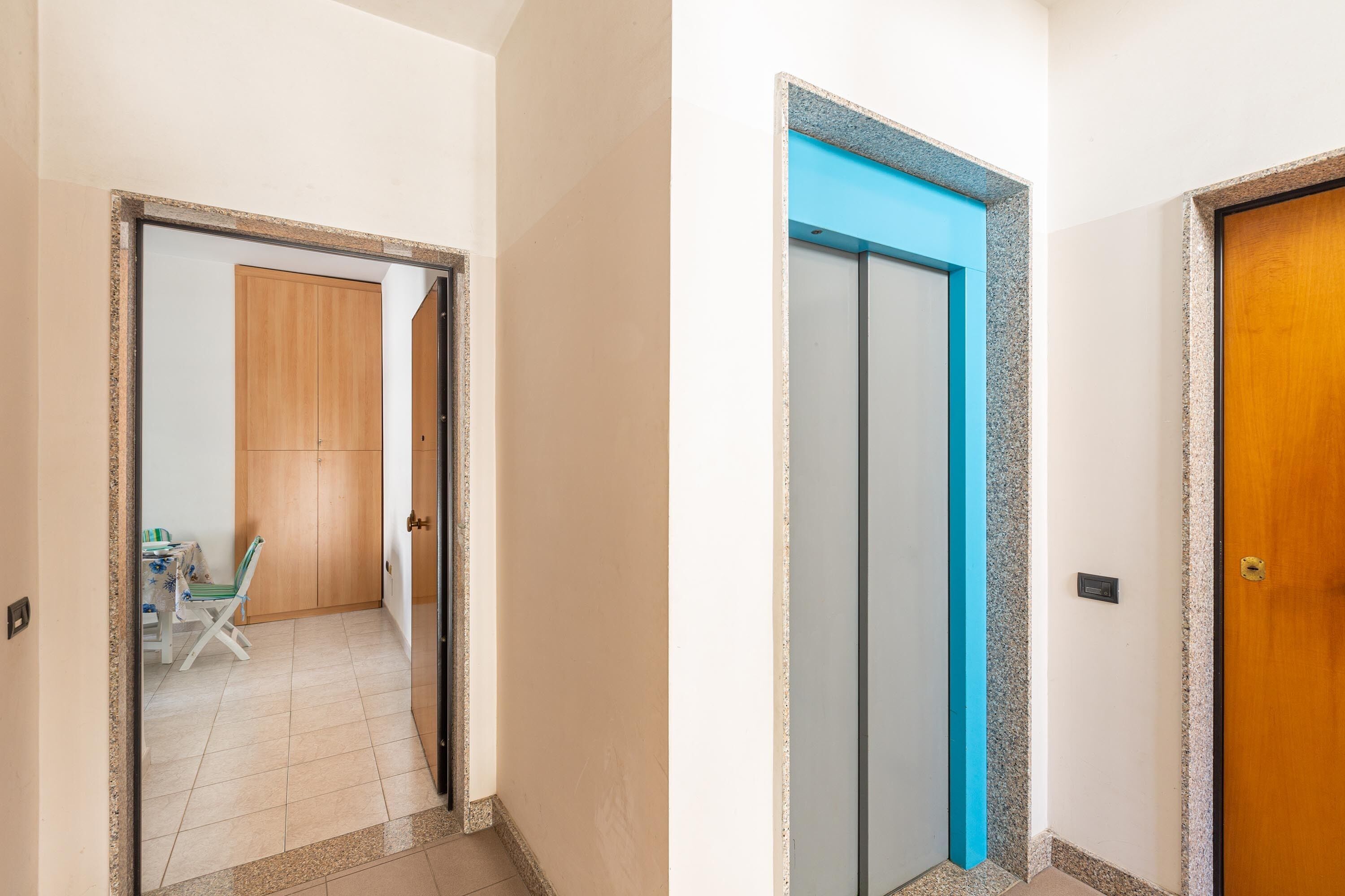 A hallway with a wooden door, a blue-framed door, and a wooden door.